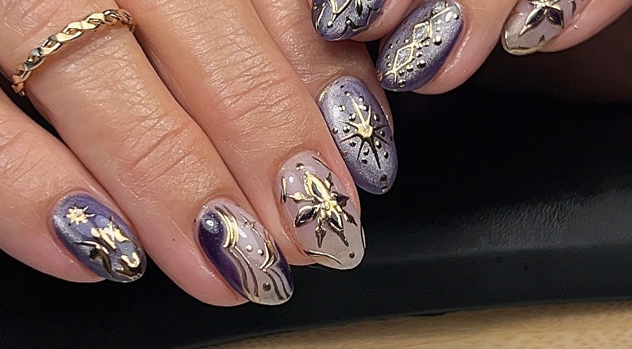Elegant celestial-themed nails at Cured by Margaret, Guelph, Ontario, CA with intricate gold and purple designs.