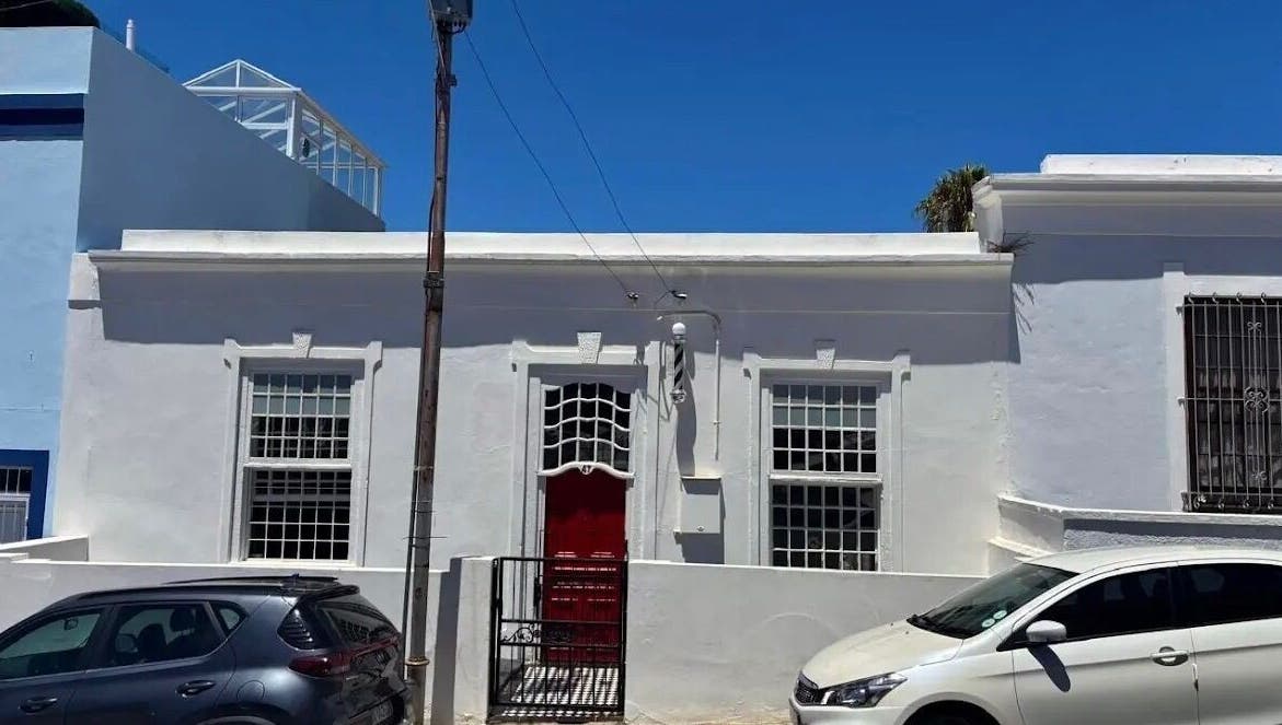 Exterior of BrowsbyFadia, a charming white building with a red door in Cape Town, Western Cape, ZA.
