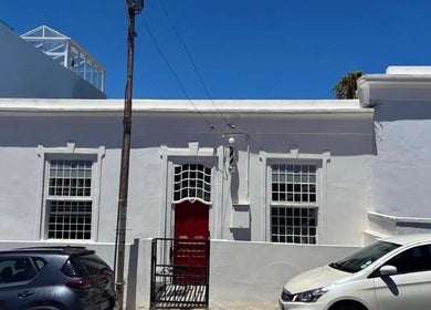Exterior of BrowsbyFadia, a charming white building with a red door in Cape Town, Western Cape, ZA.