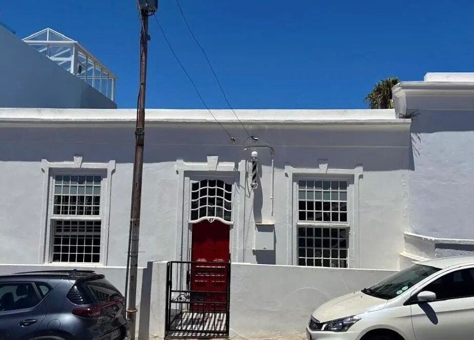 Exterior of BrowsbyFadia, a charming white building with a red door in Cape Town, Western Cape, ZA.