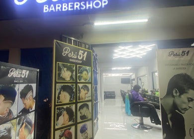Entrada iluminada de Perú 51 Barbershop Callao, mostrando cortes de tendencia en Callao, Callao, PE.