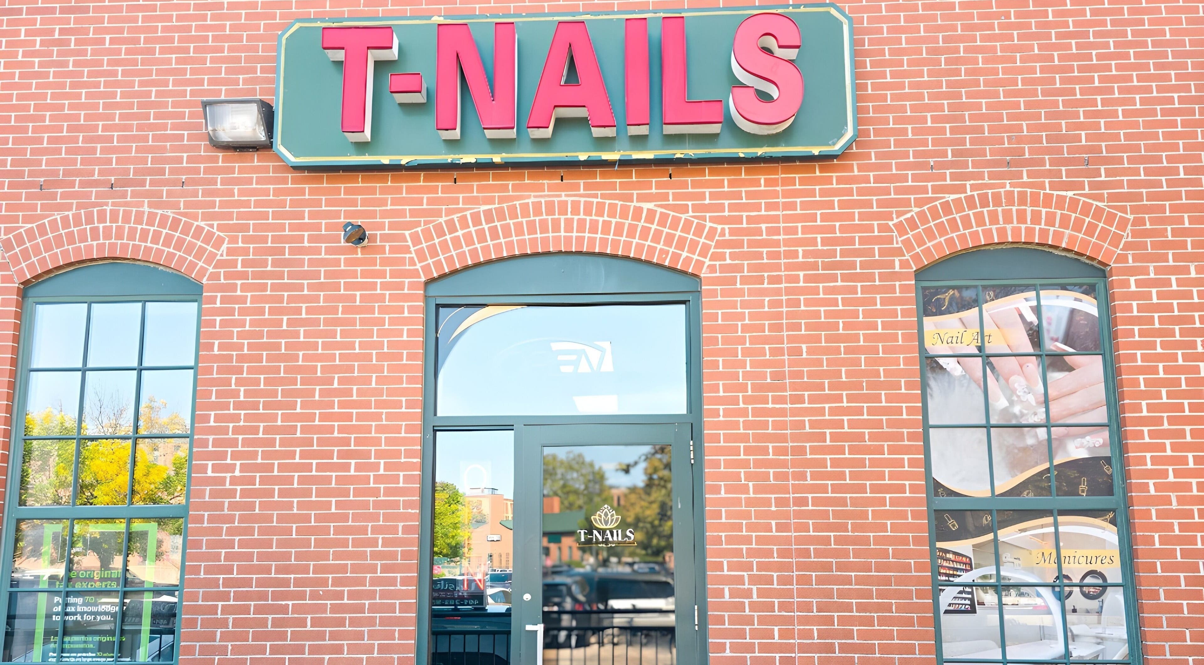 Entrance of T-Nails Glam Studio in Providence, Rhode Island, US with large signage on a brick wall.