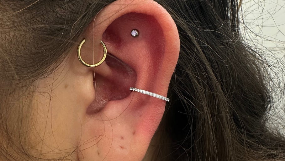 Stylish ear piercing with gold and silver hoops at ILW Body Piercing, Glenfield, England, GB.
