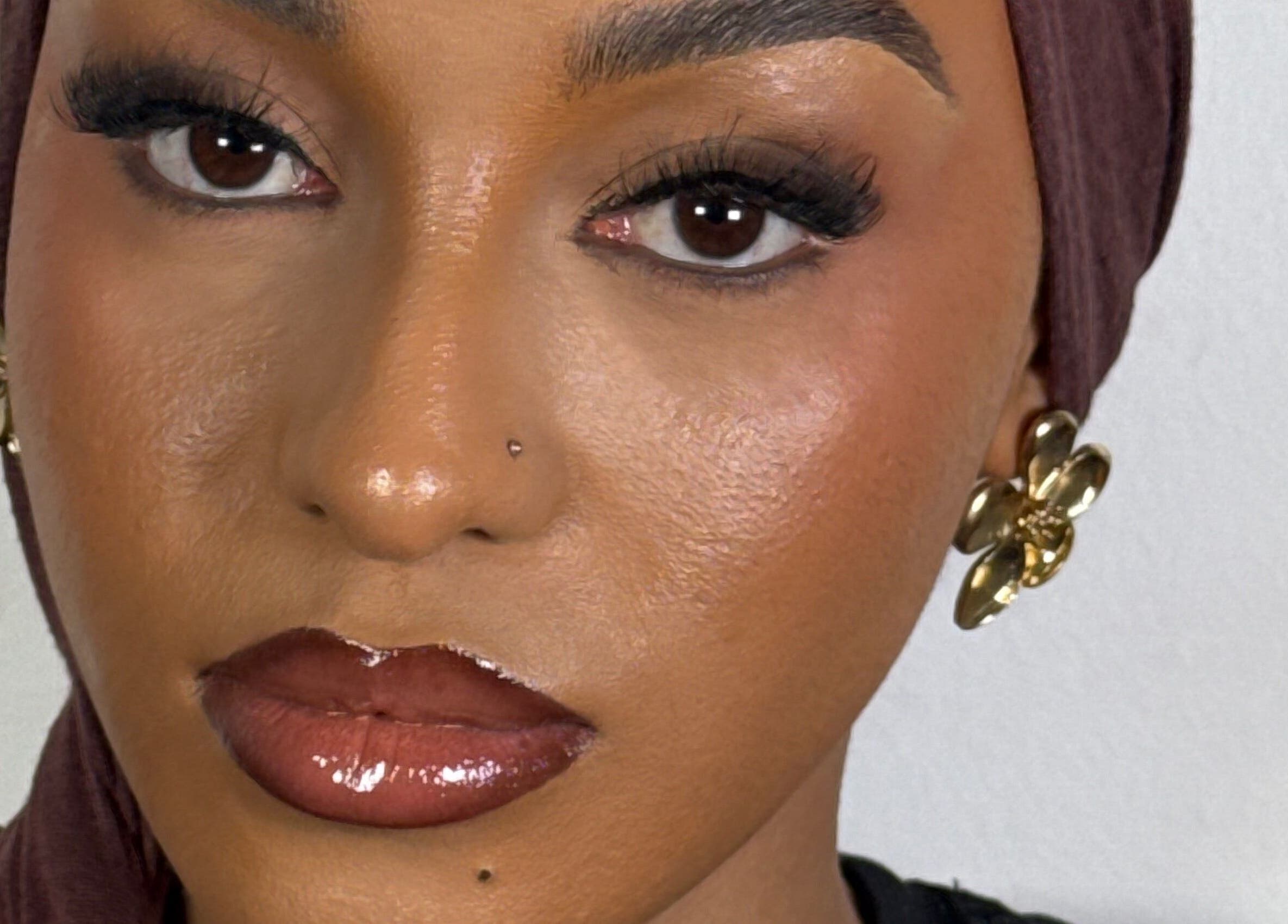 Close-up of a model with flawless makeup and gold earrings at INTISAR, London, England, GB.