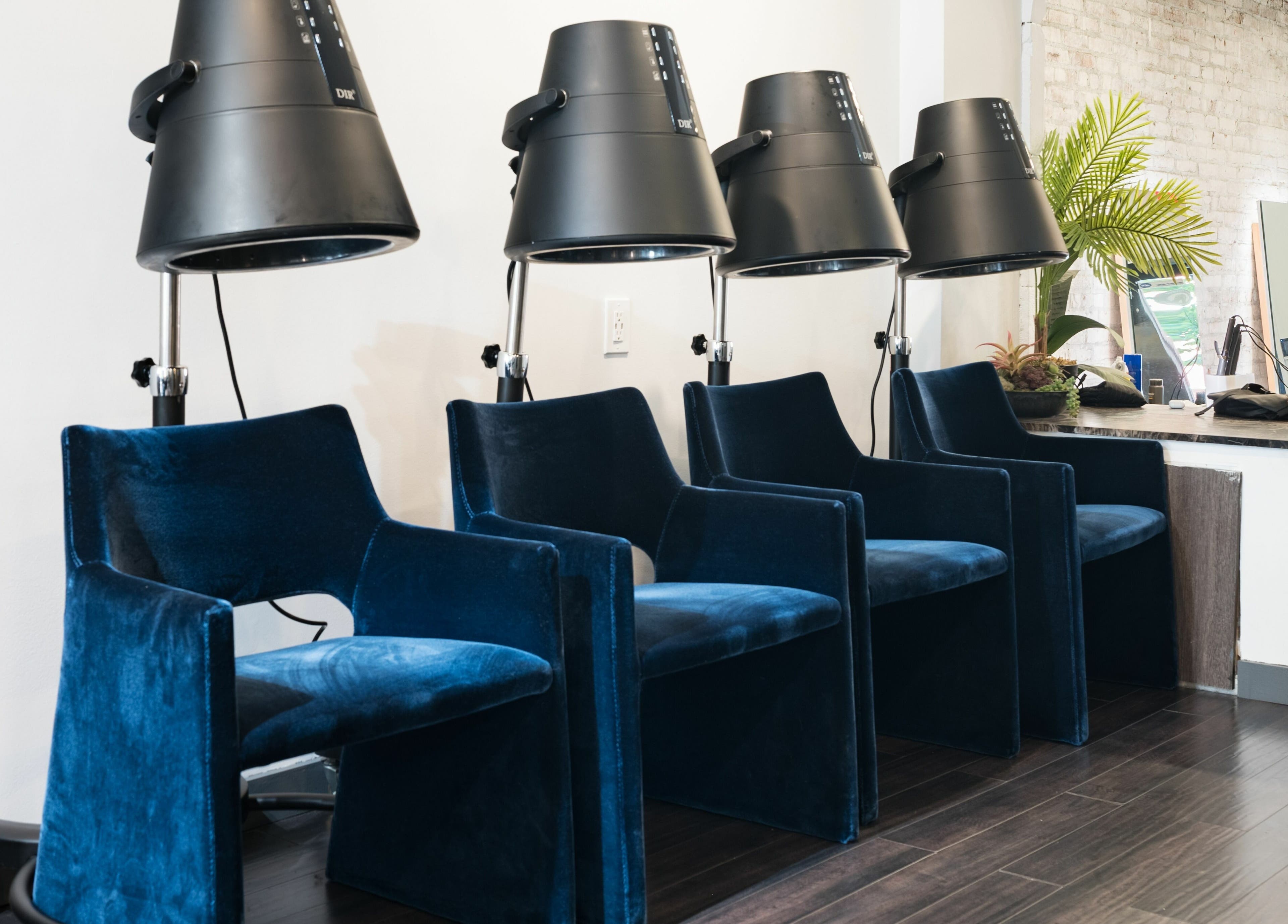 Plush blue chairs under modern dryers at H2 Salon Brooklyn, New York, New York, US creating a sleek atmosphere.