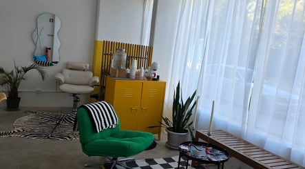 Interior moderno do Chrome Studio em Lisboa com cadeira verde e armário amarelo brilhante.
