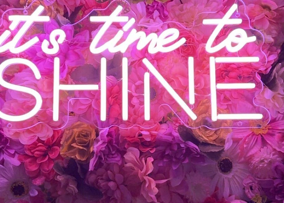 Neon sign 'It's time to shine' with floral backdrop at Beauty Girl Studios, Toronto, Ontario, CA.