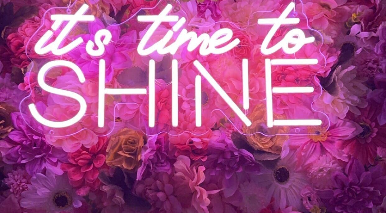 Neon sign 'It's time to shine' with floral backdrop at Beauty Girl Studios, Toronto, Ontario, CA.