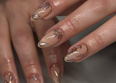 Elegant nail art design at Kallos Nails, Racine, Wisconsin, US, featuring purple and gold accents.