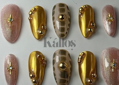 Elegant nail designs at Kallos Nails, Racine, Wisconsin, US showcasing gold and pink embellishments.