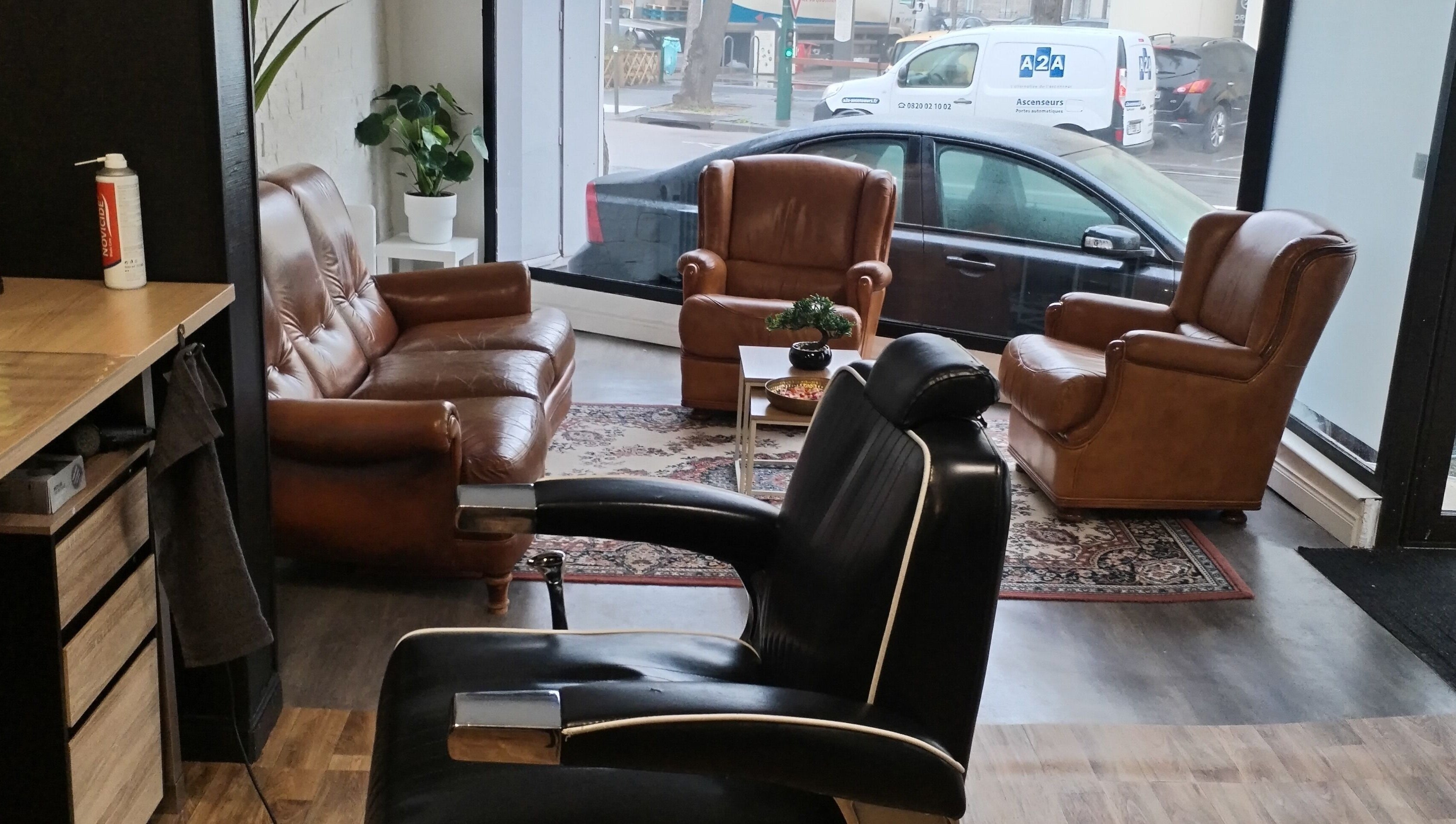 Intérieur élégant de l'Hair Frais à Reims, Grand Est, FR, avec fauteuils en cuir et plante verte.