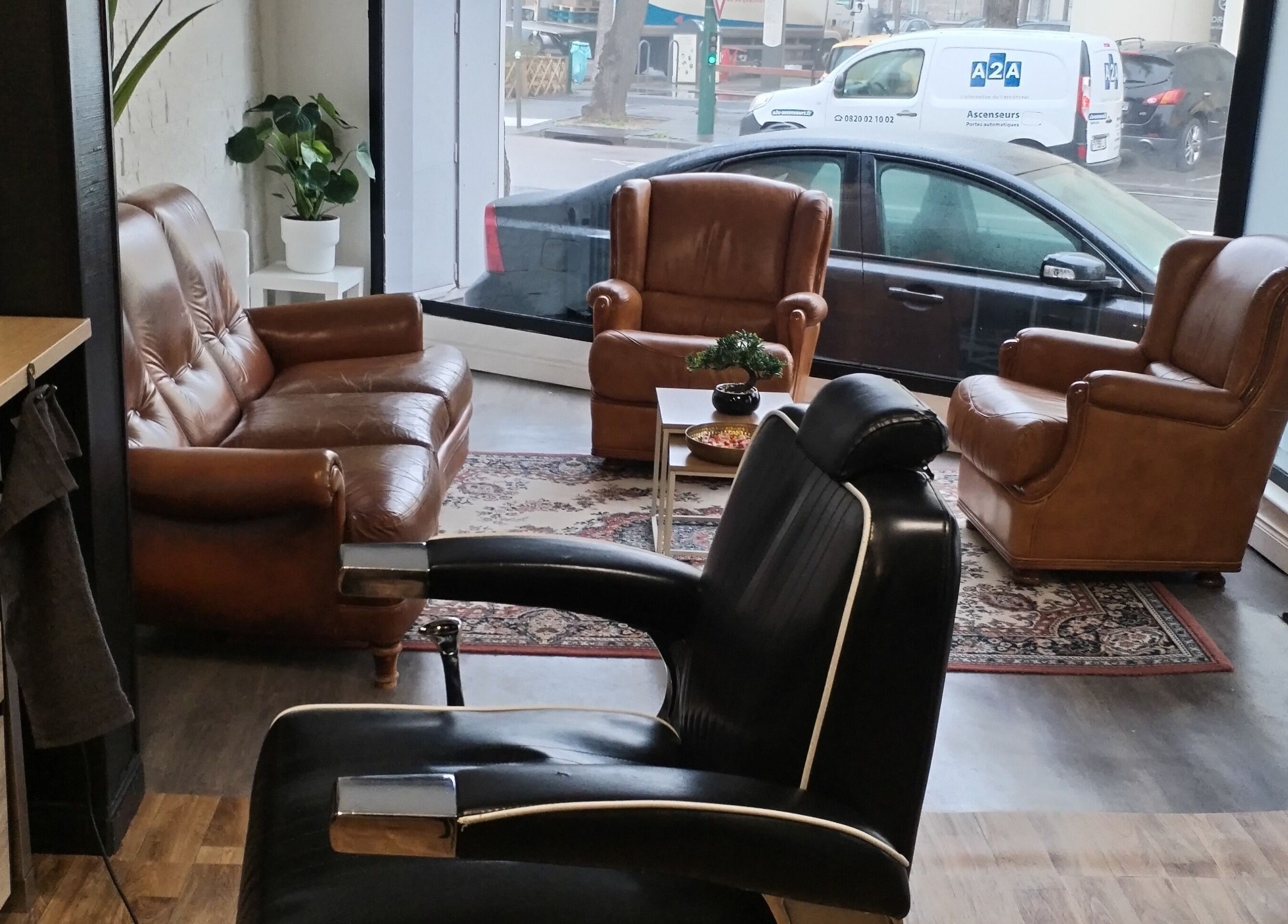 Intérieur élégant de l'Hair Frais à Reims, Grand Est, FR, avec fauteuils en cuir et plante verte.