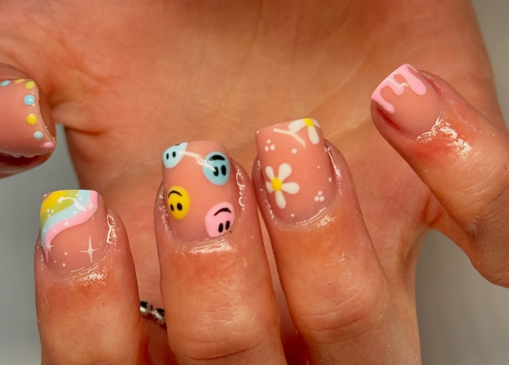 Vibrant nail art with smiley faces and daisies at Nailsby Georgia, Saint Helens, England, GB.