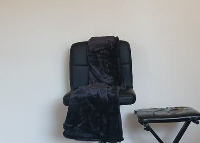 Comfortable black chair with a soft throw at Worthy Beauty, Johannesburg, Gauteng, ZA, ideal for relaxation.