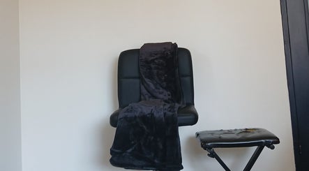 Comfortable black chair with a soft throw at Worthy Beauty, Johannesburg, Gauteng, ZA, ideal for relaxation.