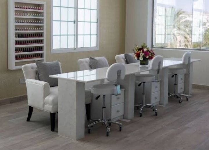 Elegant nail salon interior at Hadeelita Beauty Lounge, مسقط, محافظة مسقط, OM with plush chairs and nail polish display.