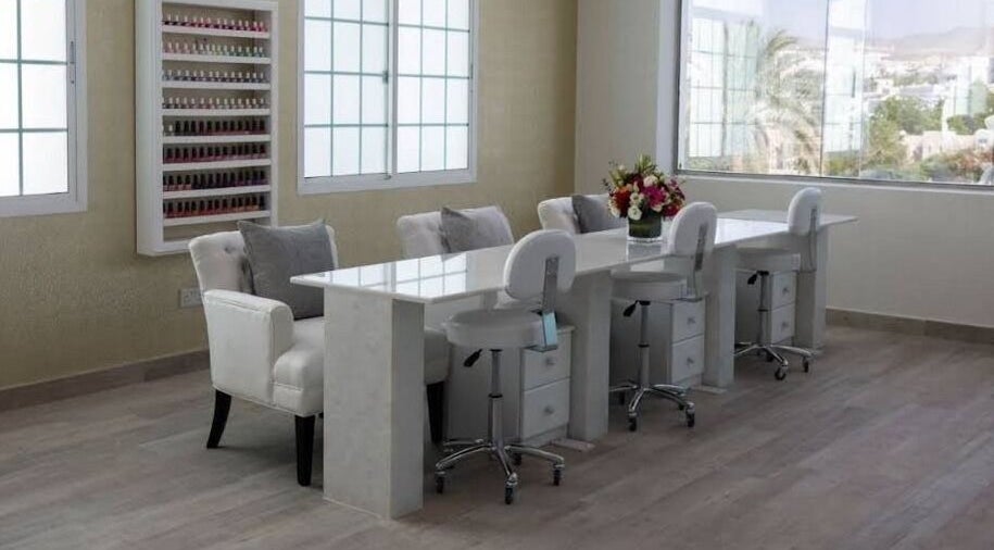 Elegant nail salon interior at Hadeelita Beauty Lounge, مسقط, محافظة مسقط, OM with plush chairs and nail polish display.
