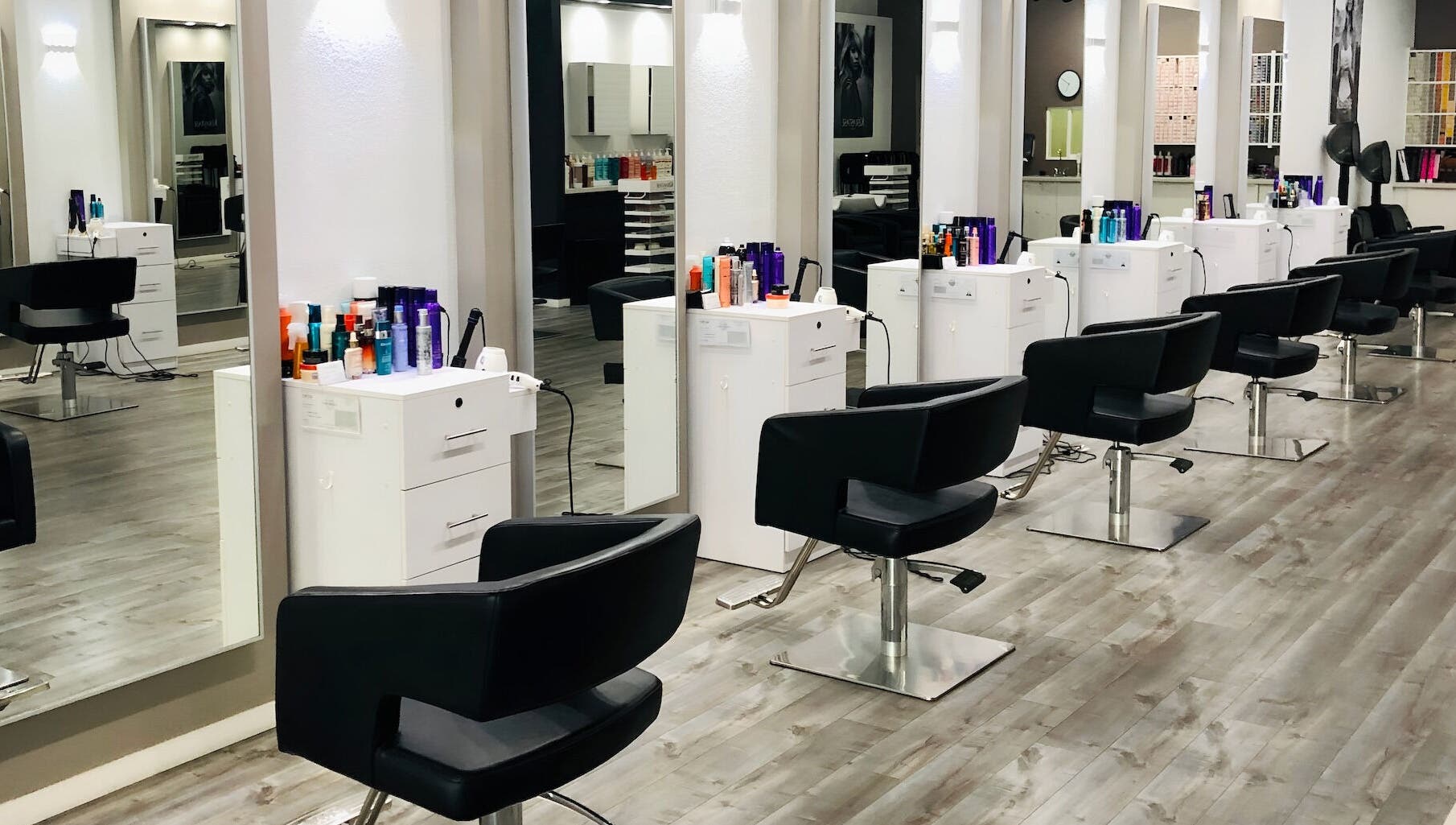 Modern styling stations at Miva Salon - B Street, Hayward, California, US, with sleek black chairs.