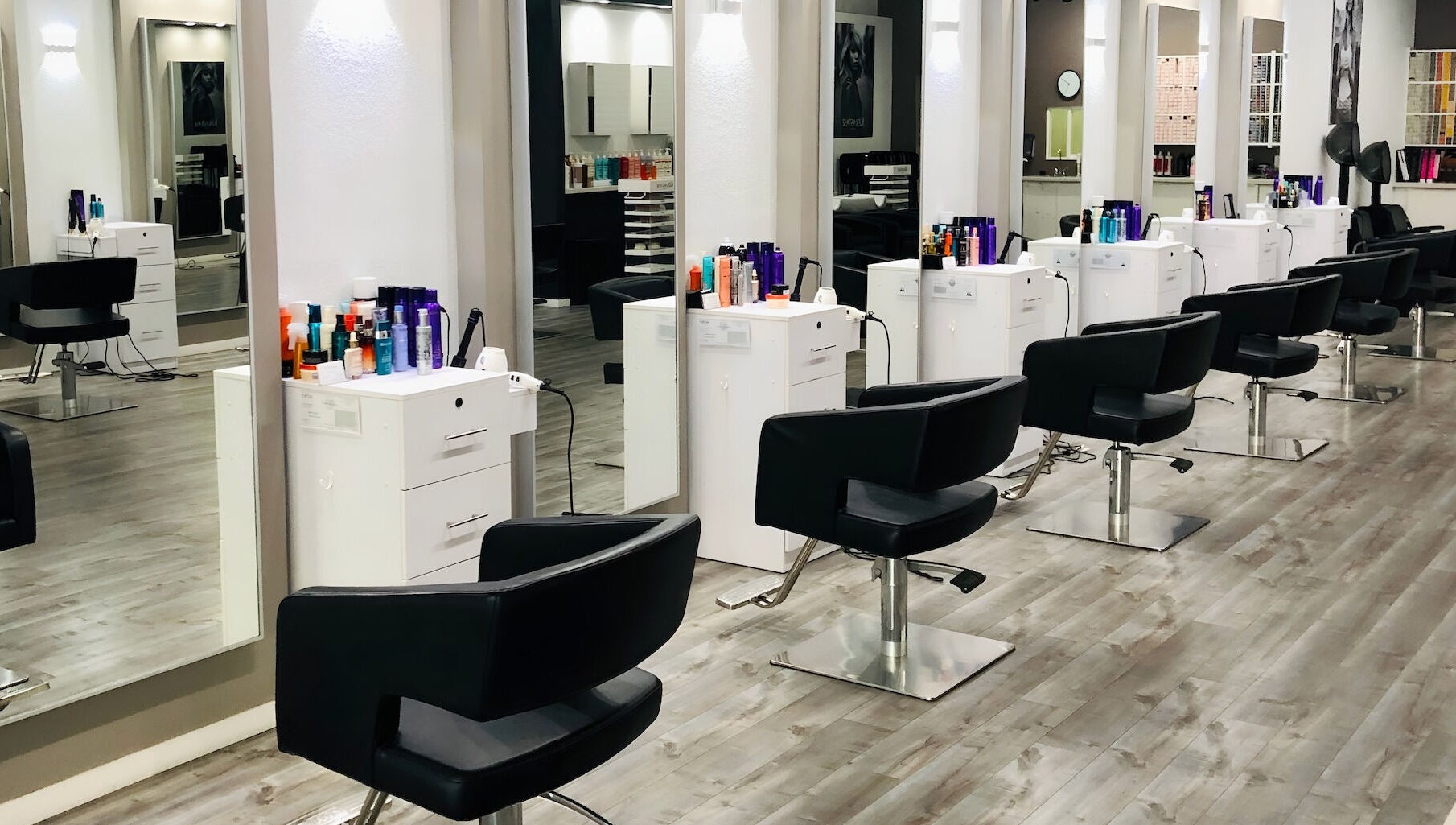 Modern styling stations at Miva Salon - B Street, Hayward, California, US, with sleek black chairs.