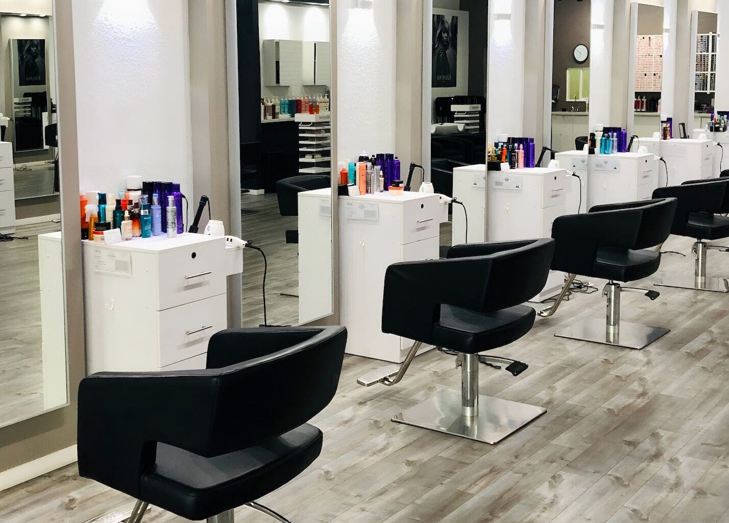 Modern styling stations at Miva Salon - B Street, Hayward, California, US, with sleek black chairs.