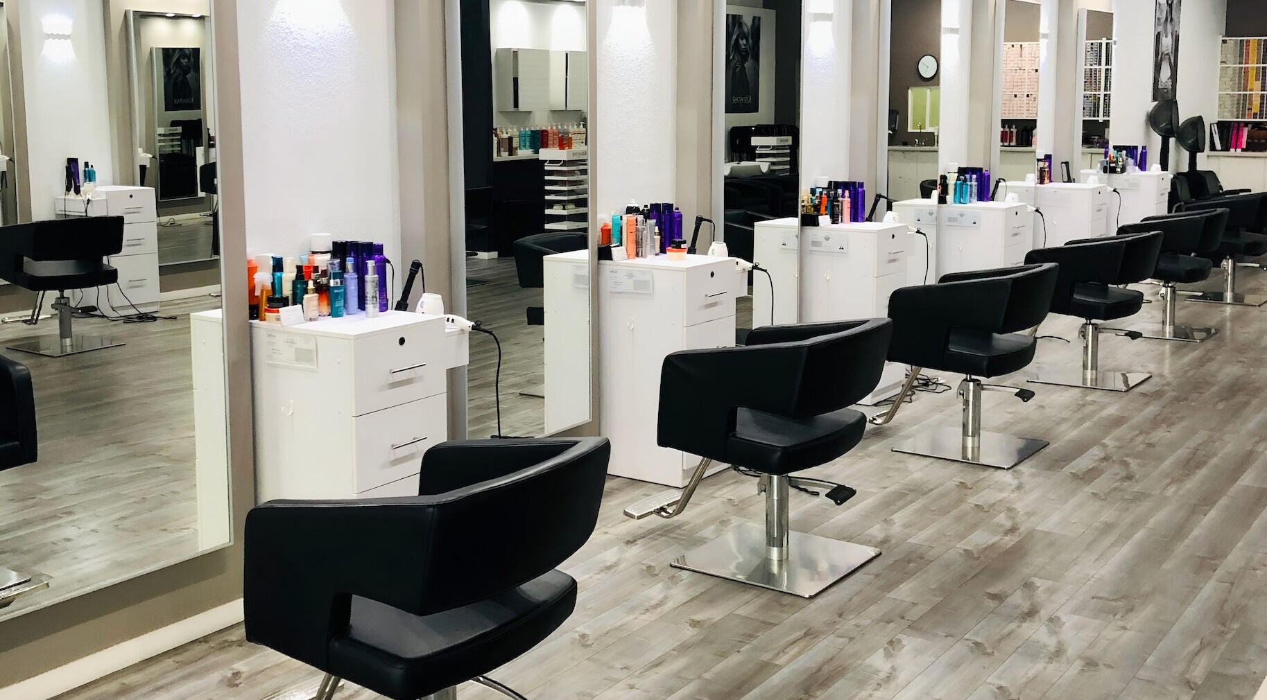 Modern styling stations at Miva Salon - B Street, Hayward, California, US, with sleek black chairs.