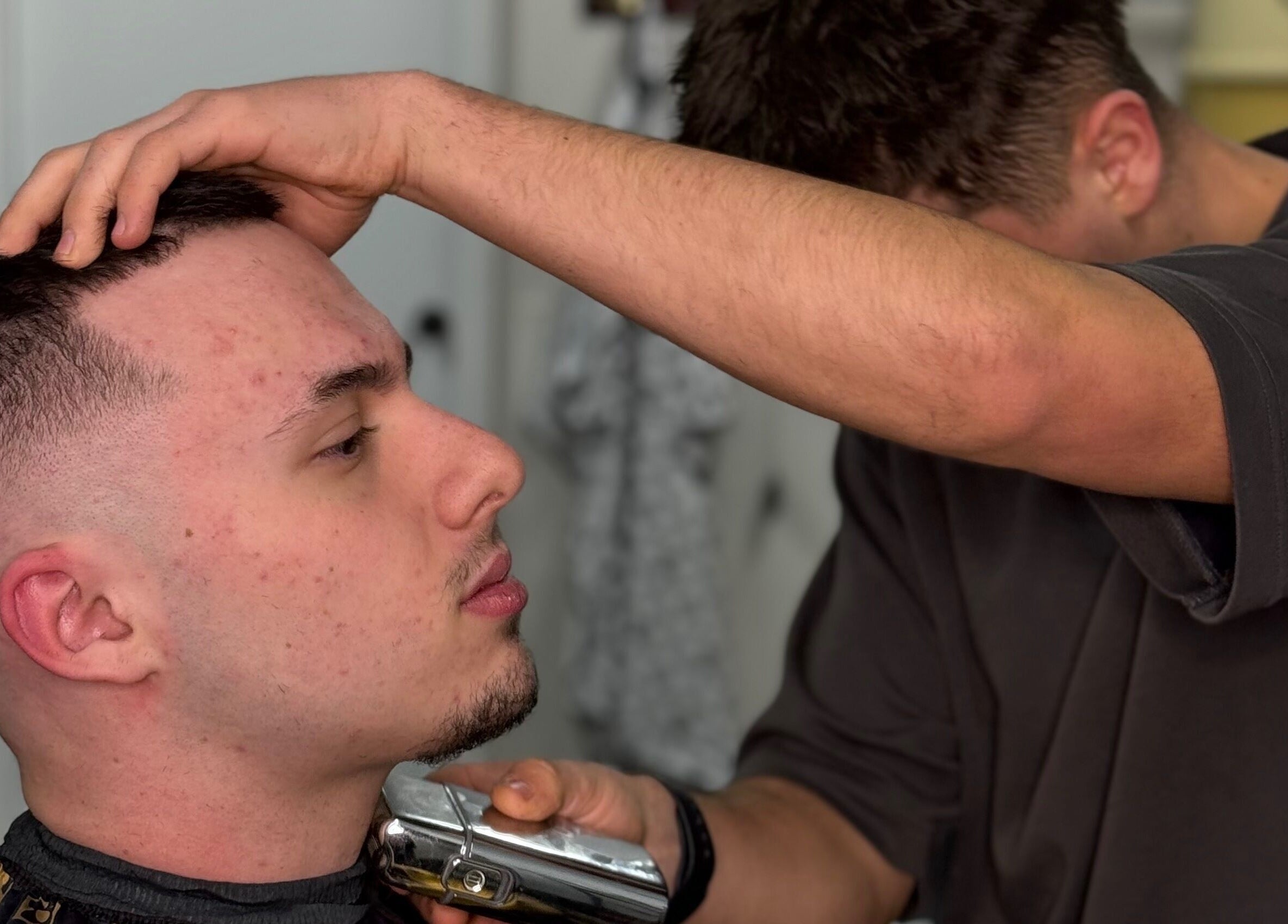 Barber giving a precise haircut at Chuckz Cutz, Melbourne, Victoria, AU. Close-up of expert styling.