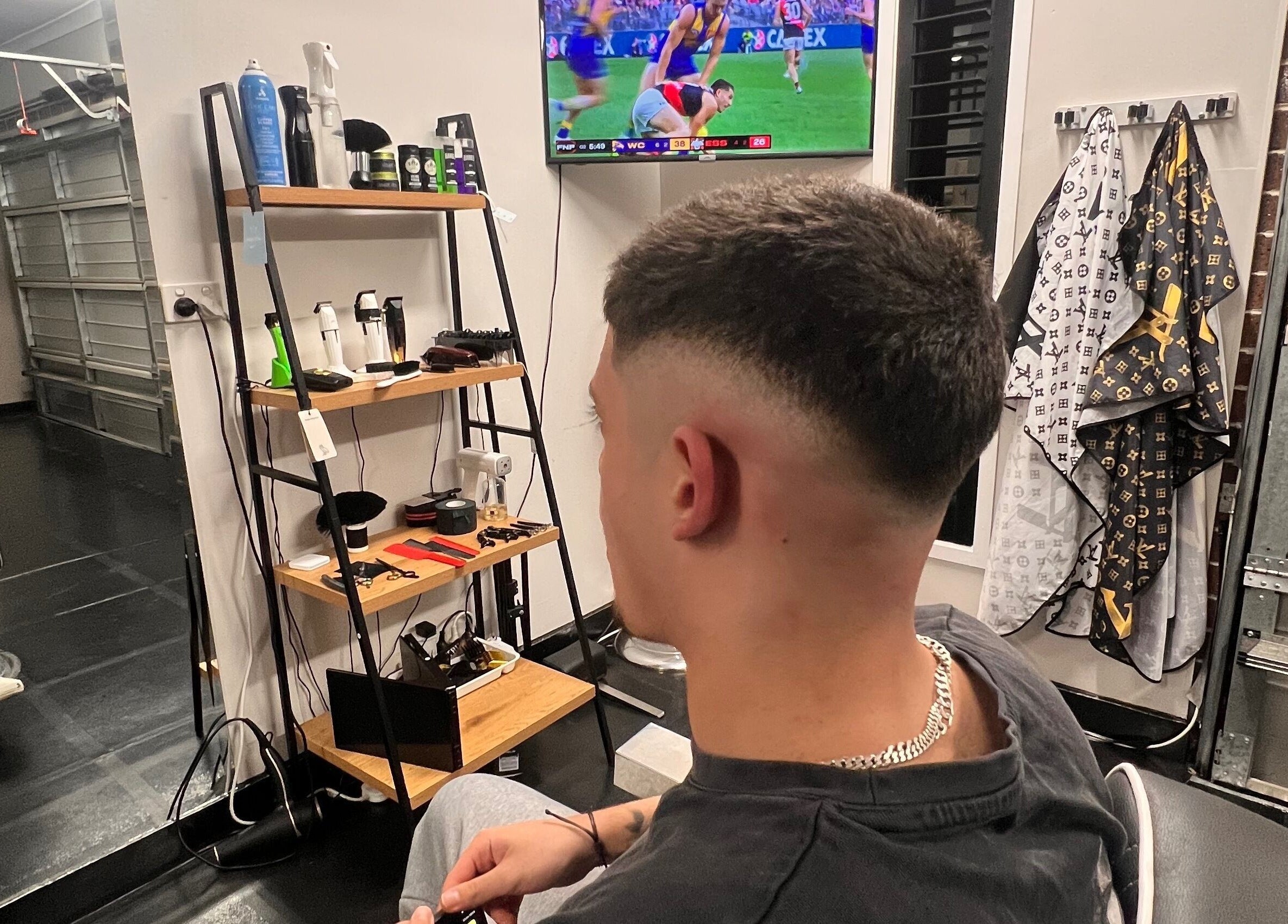 A stylish haircut at Chuckz Cutz in Melbourne, Victoria, AU. Modern interior with tools and a TV screen in view.