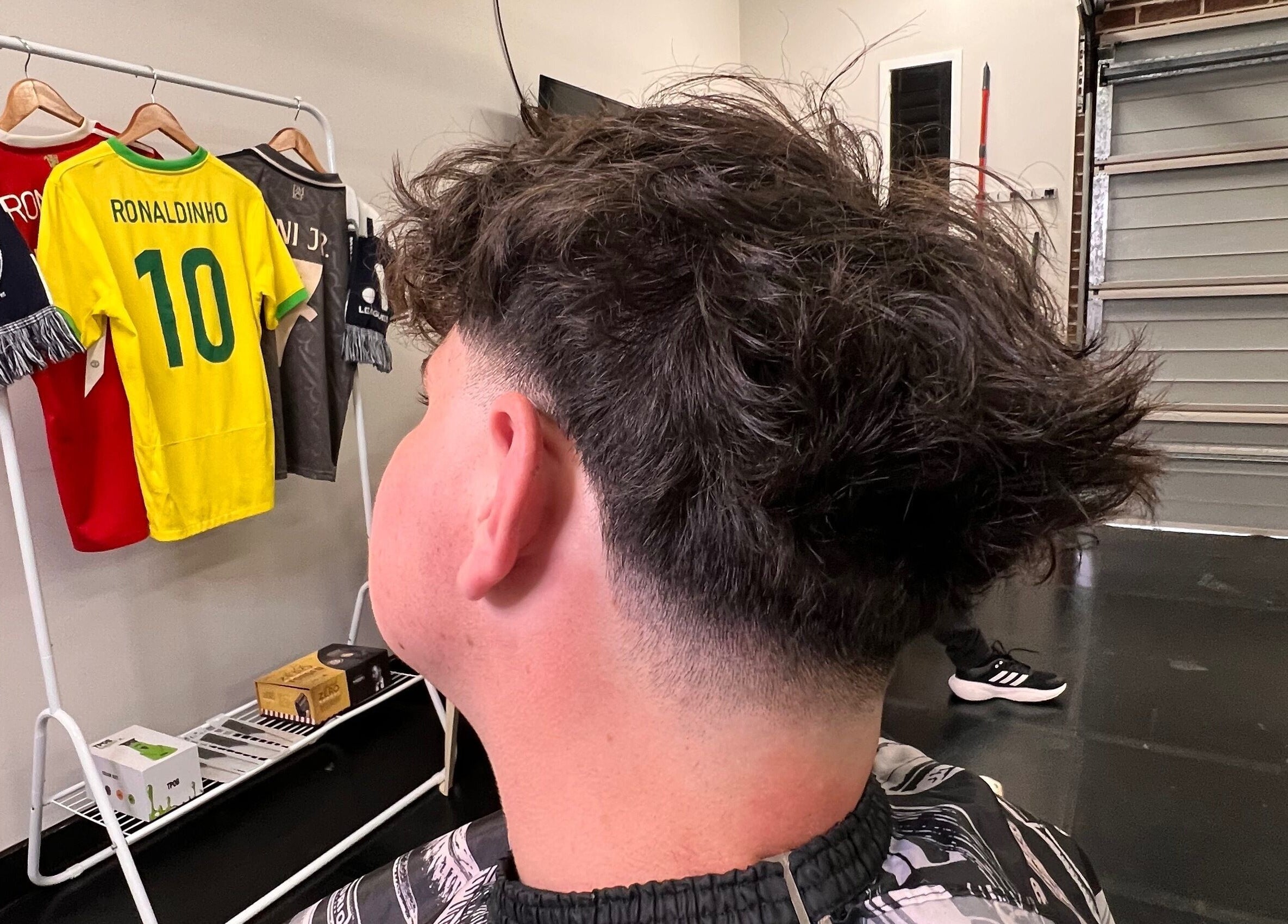 Fresh stylish haircut at Chuckz Cutz, Melbourne, Victoria, AU, with jerseys in the background.