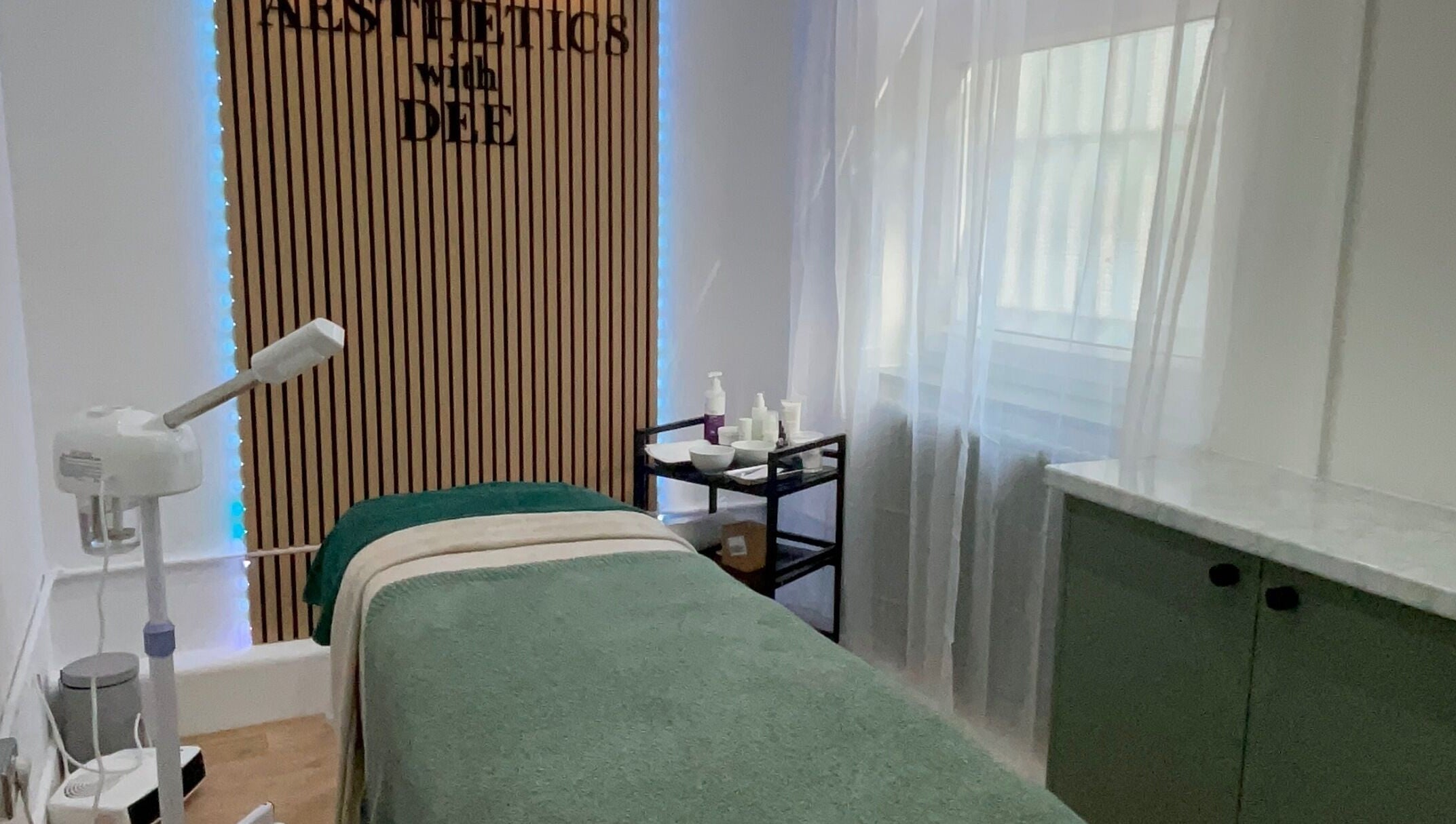 Calm treatment room at Aesthetics with Dee, London, England, GB, featuring a bed and skincare products.