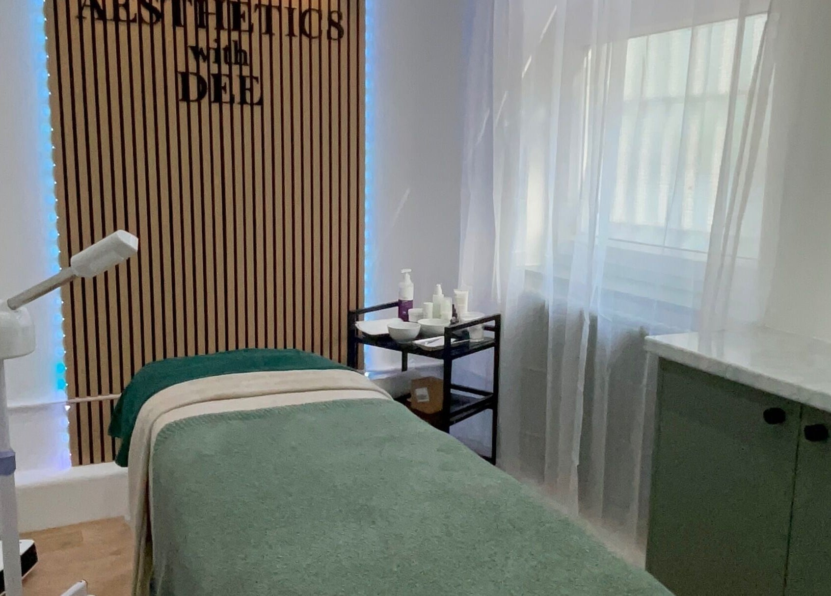 Calm treatment room at Aesthetics with Dee, London, England, GB, featuring a bed and skincare products.