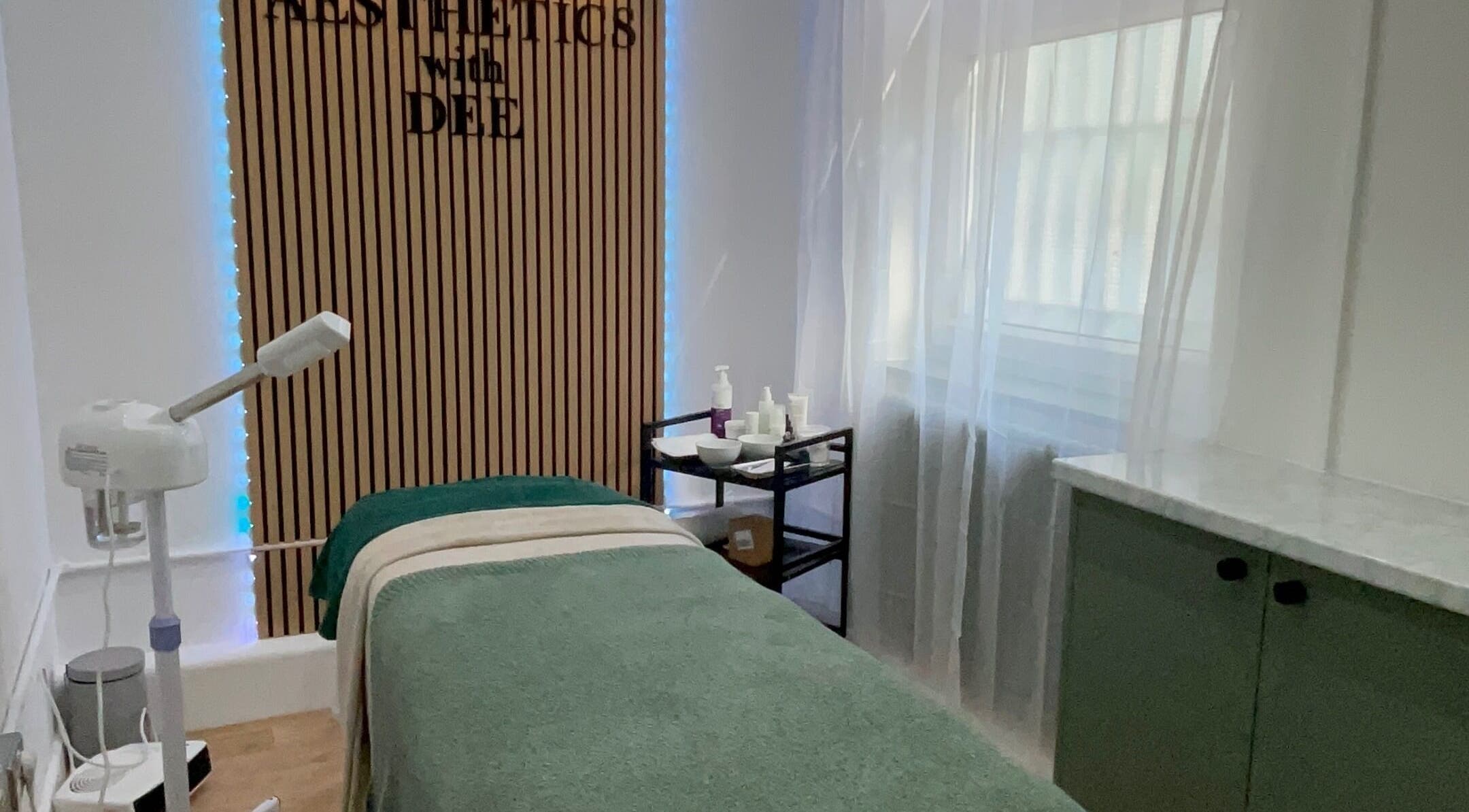 Calm treatment room at Aesthetics with Dee, London, England, GB, featuring a bed and skincare products.