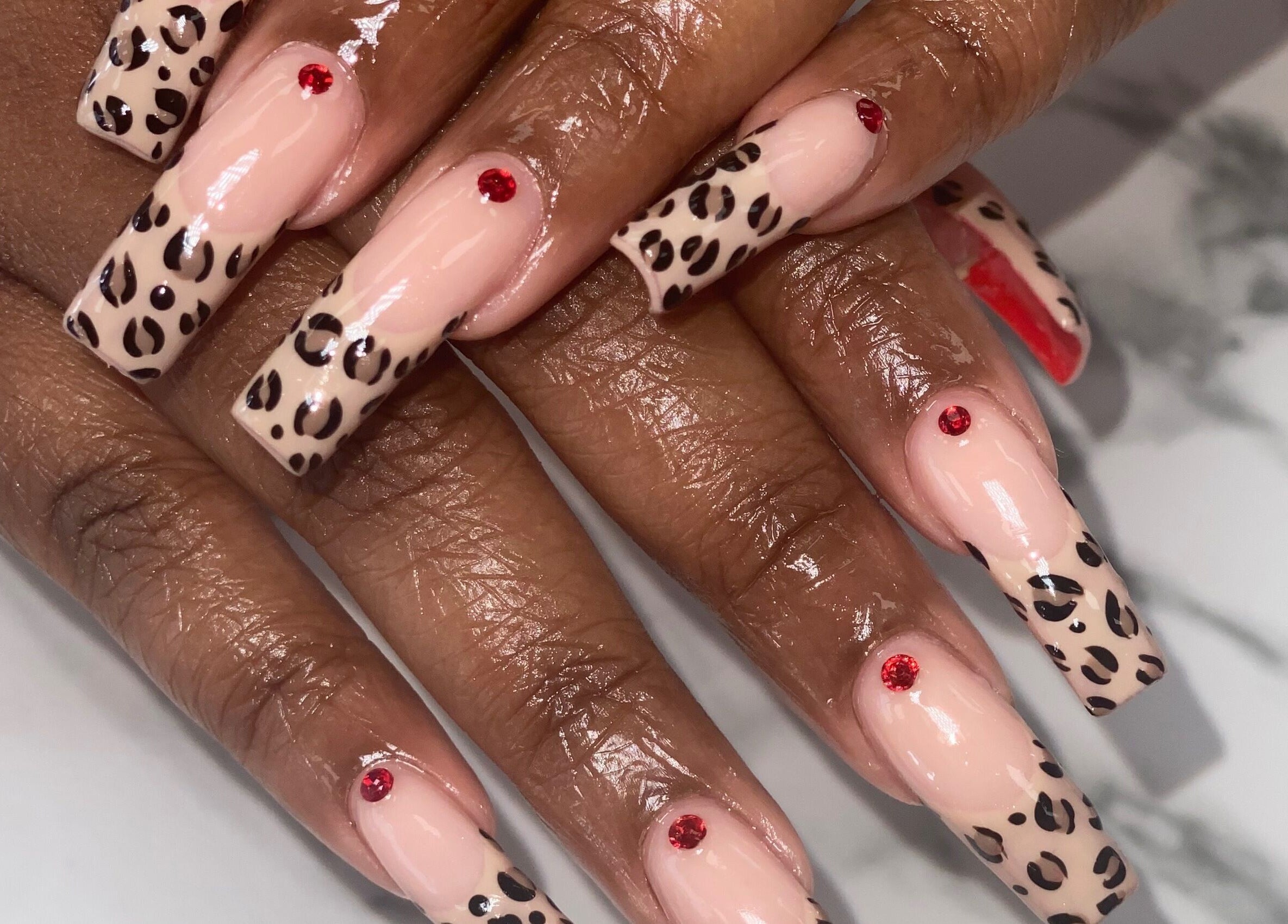 Stylish leopard print manicure with red gems at Naild By Tee, Chicago Heights, Illinois, US.