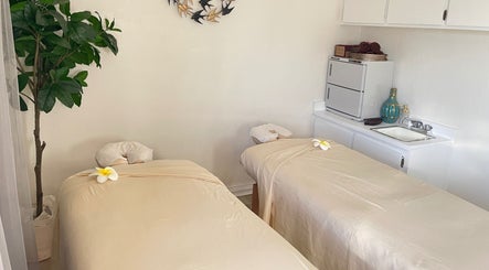 Peaceful massage room at Thai House Wellness and Spa, Sacramento, California, US, with plumeria-adorned tables.