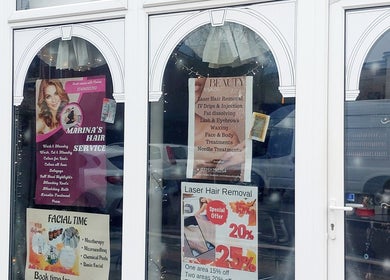 Shopfront of Palmarys in Southampton, England, GB showcasing beauty service posters through elegant arched windows.