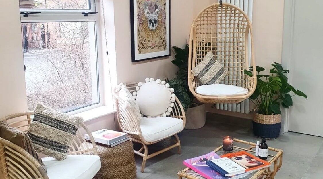 Cozy seating area with wicker chairs at Strawberry Blonde Makeup, Belfast, Northern Ireland, GB.