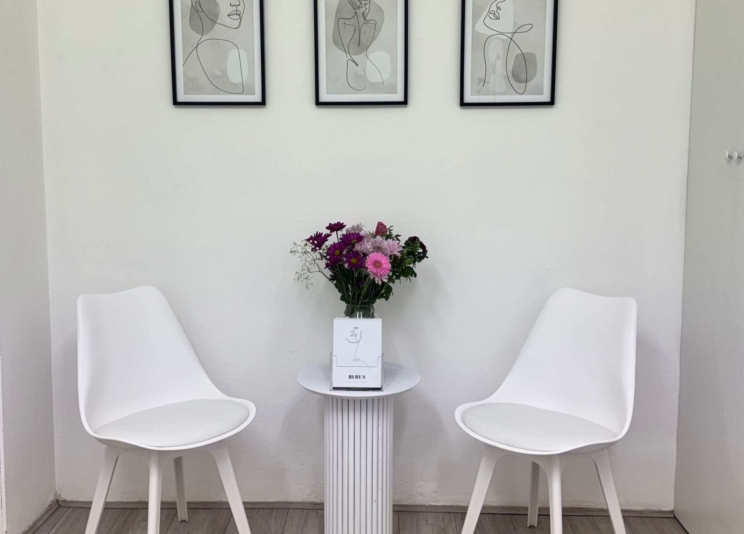 Stylish waiting area at Ruby’s Hair Skin & Laser, London, England, GB with white chairs and wall art.