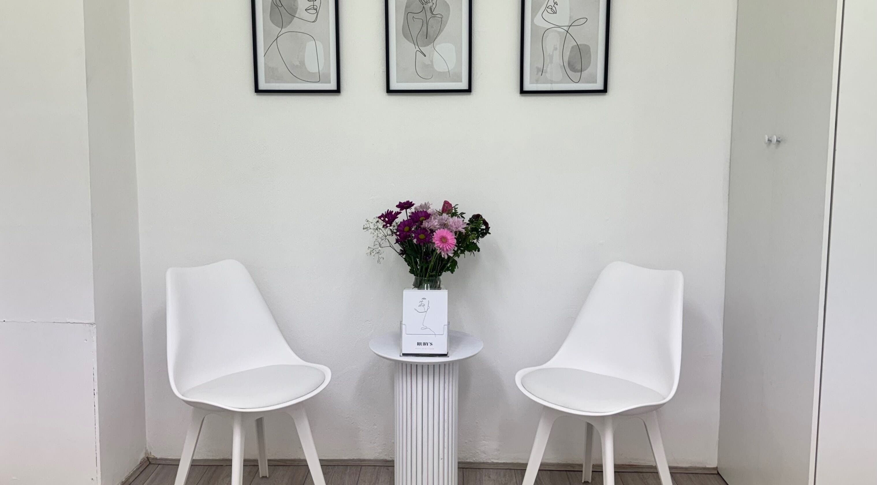 Stylish waiting area at Ruby’s Hair Skin & Laser, London, England, GB with white chairs and wall art.