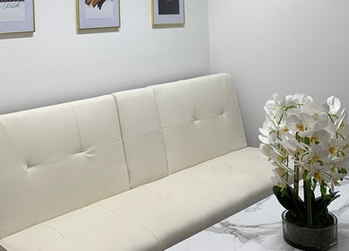 Stylish waiting area at Harley Beauty Aesthetic Clinic, Ilford, England, GB featuring a white sofa and orchids.