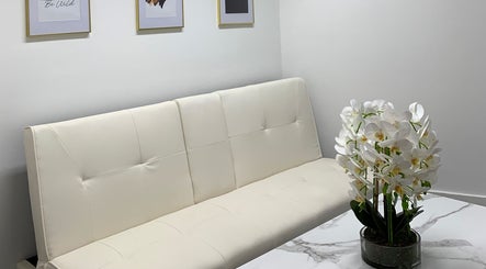 Stylish waiting area at Harley Beauty Aesthetic Clinic, Ilford, England, GB featuring a white sofa and orchids.