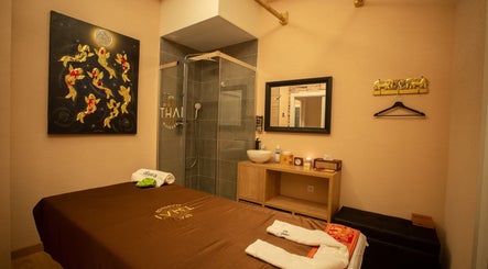 Relajante sala de masajes en Thai Spa Massage Alura, Barcelona, Catalunya, ES, con arte dorado y decoración zen.