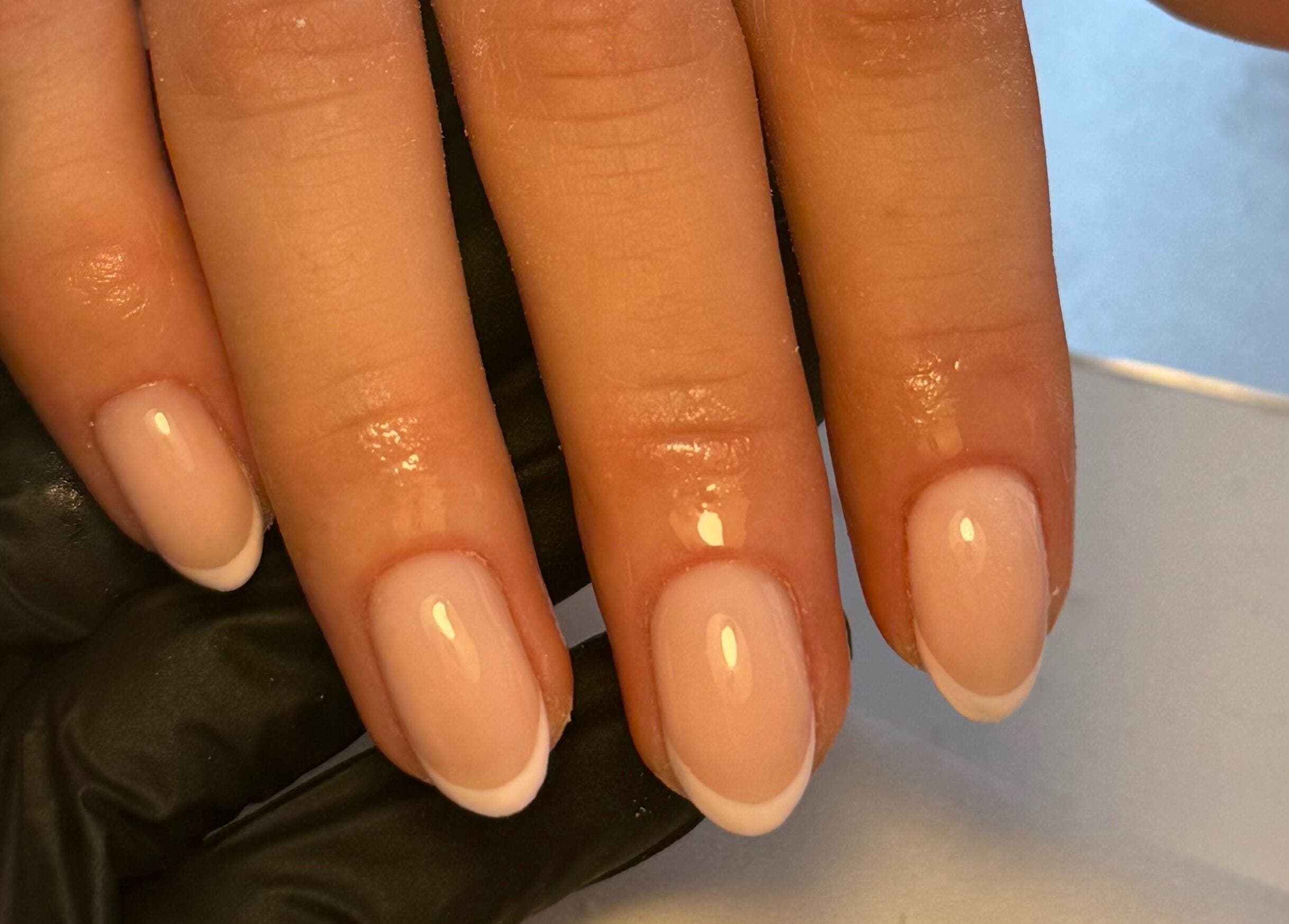 French manicure with glossy finish by Cerys Nails, Warrington, England, GB. Perfectly shaped nails displayed on hand.