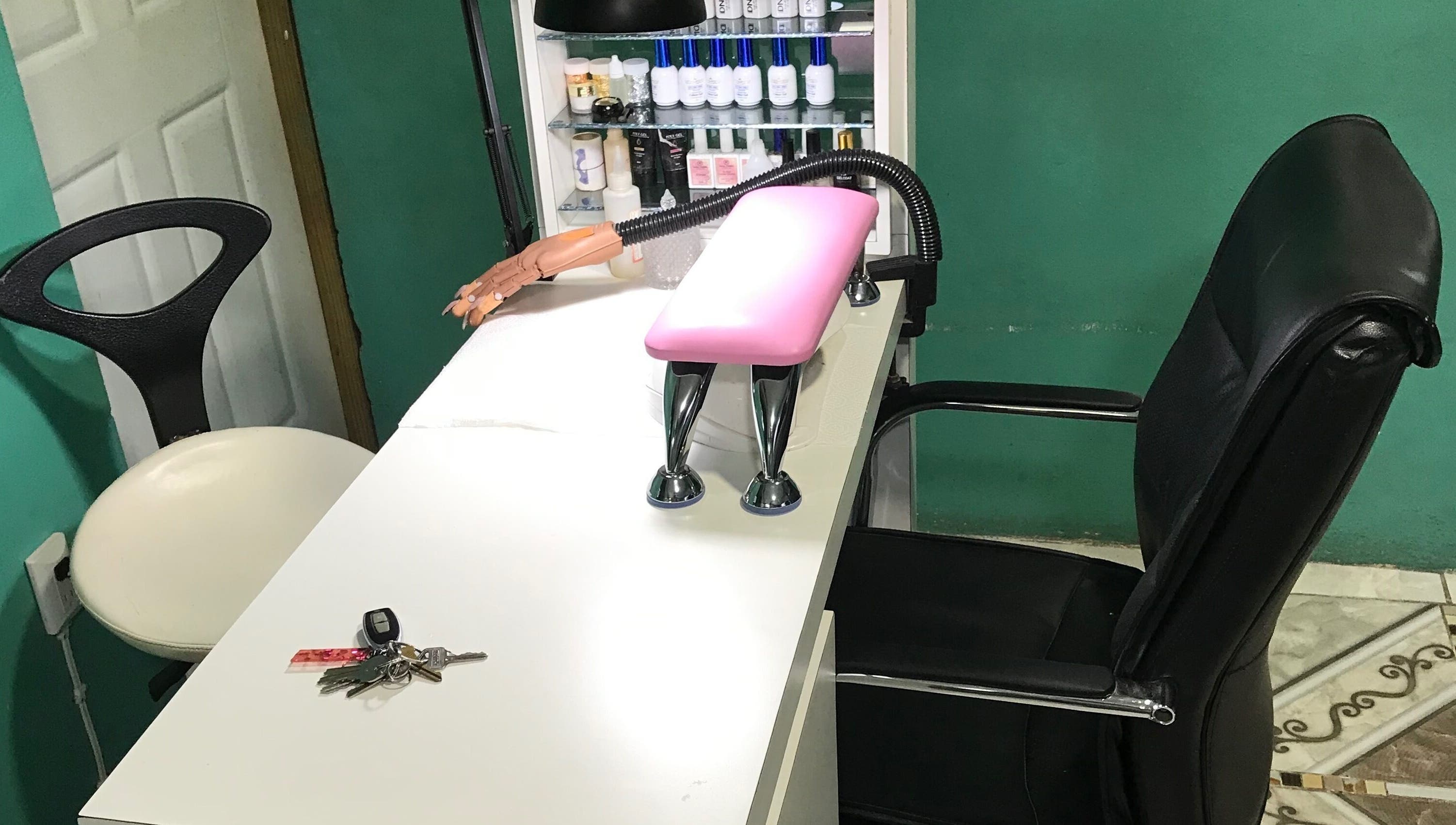 Manicure station at Pure Posh Nails, Browns Town, St. Ann Parish, JM, with a black chair and pink armrest.