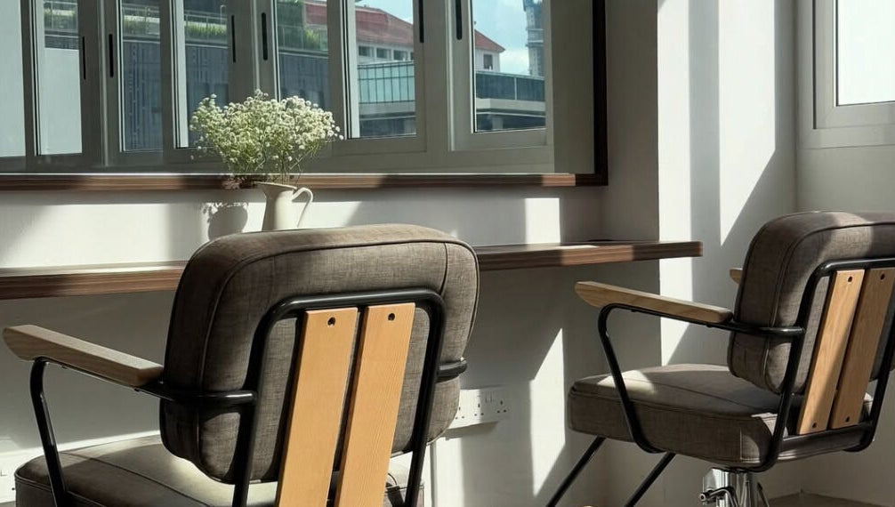 Bright salon chairs by window in Kutsurogi, Singapore, Singapore, SG, with a vase of white flowers.
