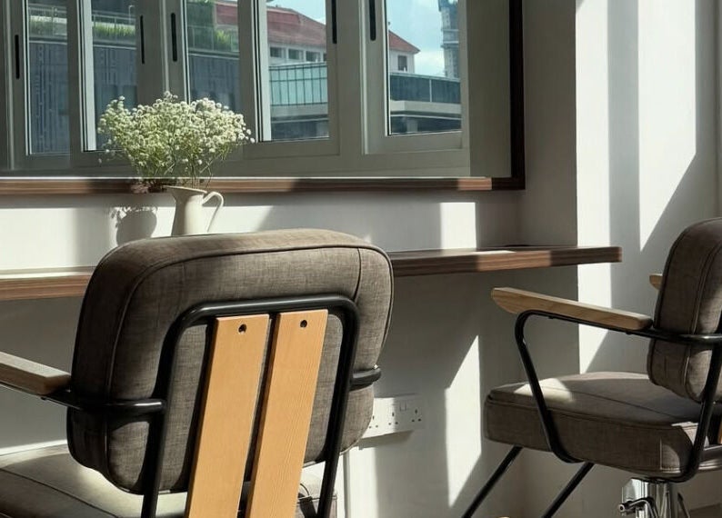Bright salon chairs by window in Kutsurogi, Singapore, Singapore, SG, with a vase of white flowers.