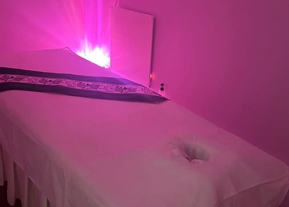 Tranquil massage room with purple lighting at Yo Spa, London, England, GB. Relaxing ambiance and comfort await.