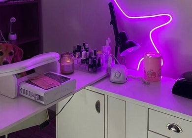Mesa de manicura en Mariecure.nails, La Florida, Región Metropolitana, CL iluminada con luz púrpura y productos.