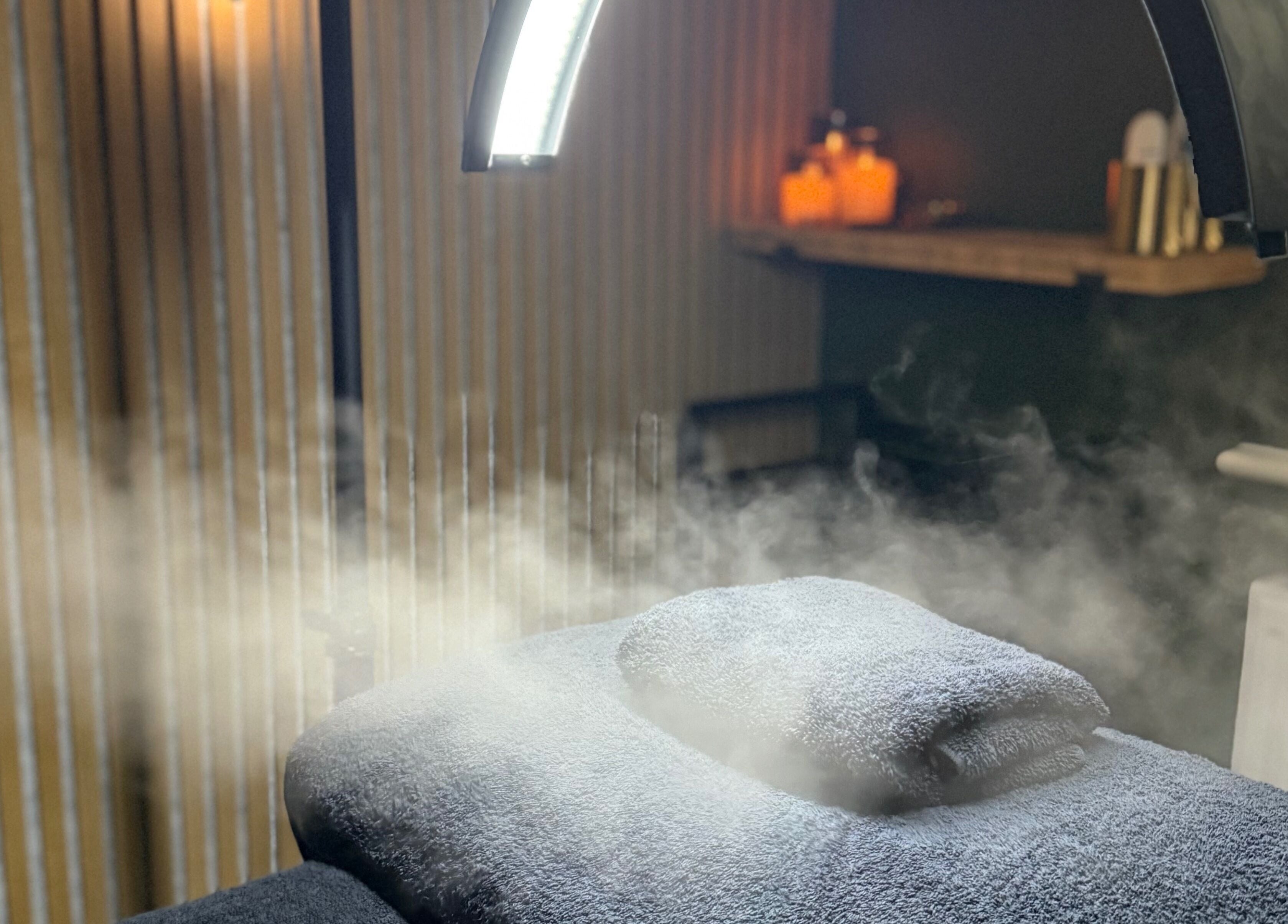 Relaxing steam therapy room at Glow and Renew Skincare, Ash, England, GB, with folded towels and ambient lighting.