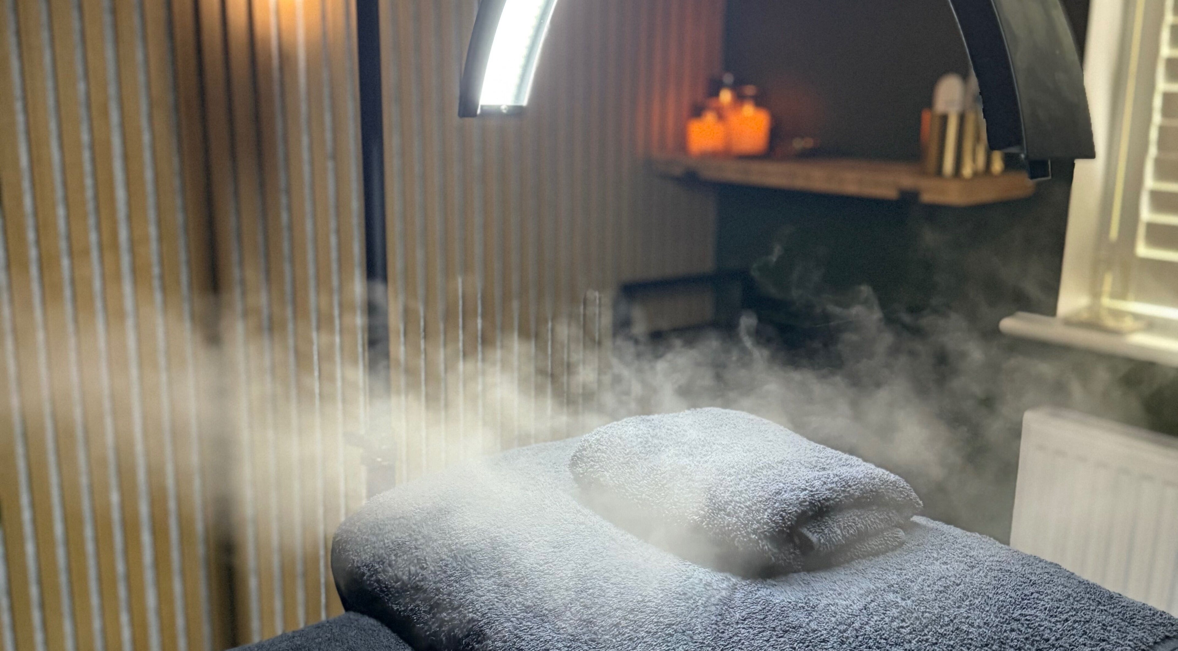 Relaxing steam therapy room at Glow and Renew Skincare, Ash, England, GB, with folded towels and ambient lighting.