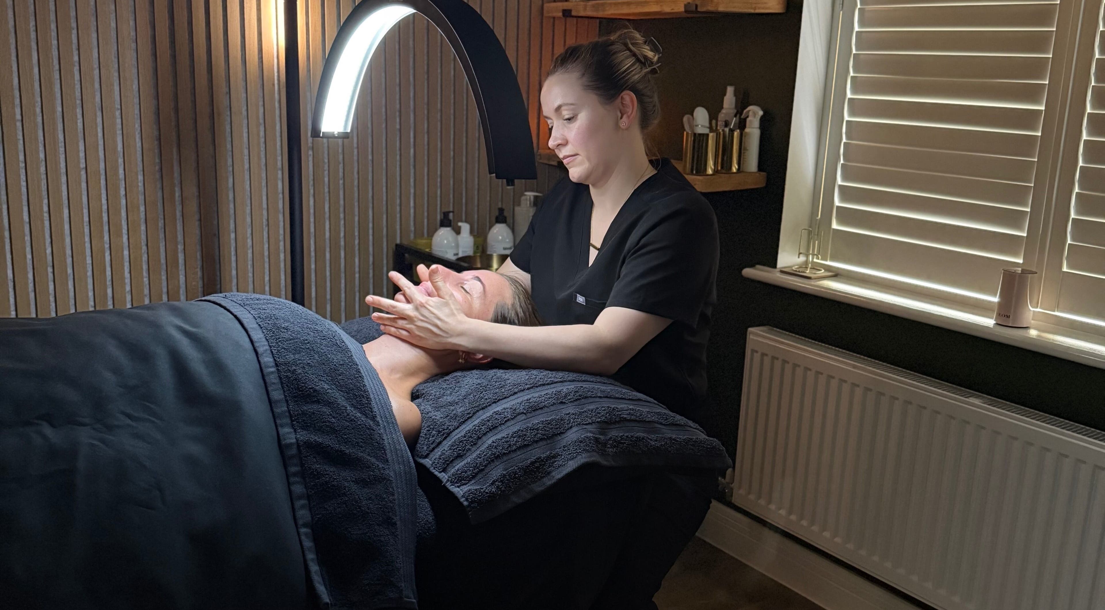 Skincare treatment at Glow and Renew Skincare, Ash, England, GB. Therapist massages client's face under cozy lighting.