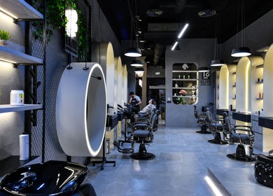 Interior of L8 Elite Barbershop in Riyadh, showcasing modern barber chairs and illuminated shelves.